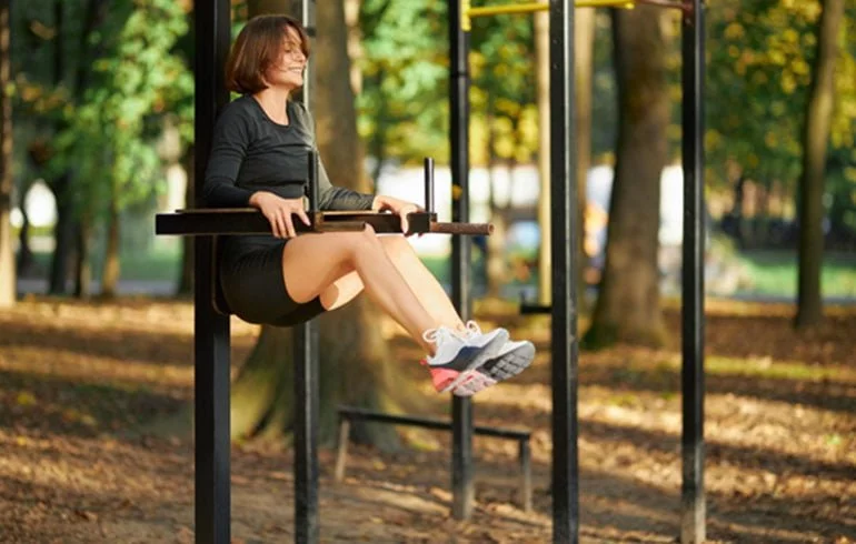 Mujer haciendo ejercicio en barras horizontales en el parque