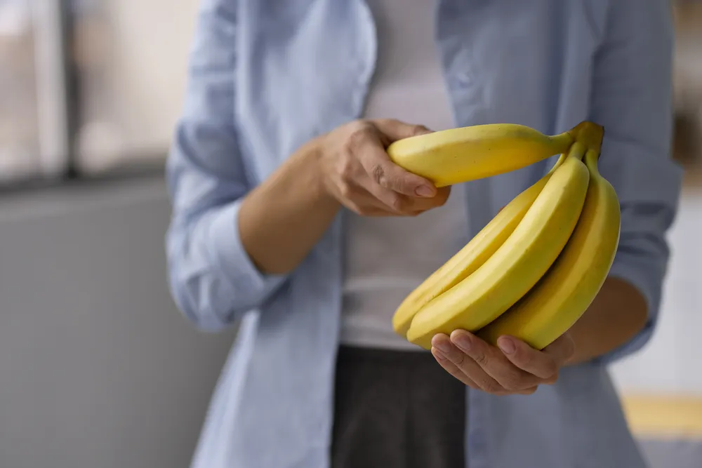 mujer sosteniendo plátanos maduros